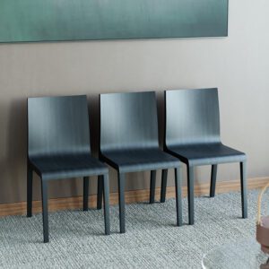 Three black minimalist visitor chairs against the wall with artwork in the background.