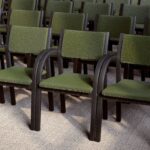 A row of classic visitors' chairs with a low back, green upholstery and a dark wood frame.